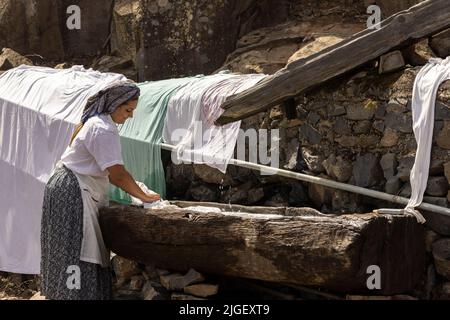 Chirche, Ténérife, 10 juillet 2022. Les jeunes filles lavant des vêtements dans un bac en bois à la station de lavage commune. Les villageois célèbrent la Día de tradiciones, jour des traditions dans le petit village de montagne où ils rendaient des scènes du style de vie rural vécu par leurs ancêtres en 1940s Banque D'Images