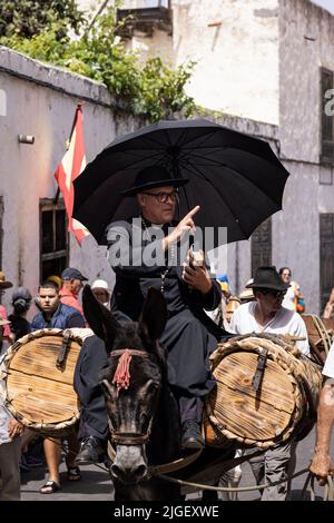 Chirche, Ténérife, 10 juillet 2022. Le sacrificateur au dos d'une mule bénit les gens comme il passe. Les villageois célèbrent la Día de tradiciones, jour des traditions dans le petit village de montagne où ils rendaient des scènes du style de vie rural vécu par leurs ancêtres en 1940s Banque D'Images