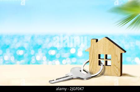 Modèle de maison et clé sur une plage de sable avec mer et ciel sur le fond Banque D'Images