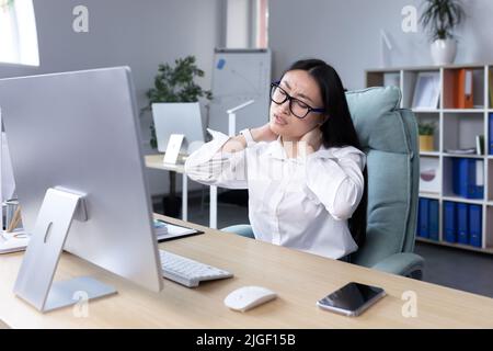 Jeune femme asiatique belle employée de bureau, indépendant, femme d'affaires en lunettes et chemise blanche, assis à la table à l'ordinateur, fatigué, échappement Banque D'Images