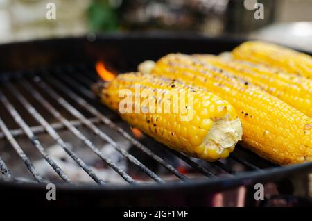 Quatre délicieux cornes sucrées sur la rafle rôtisant sur un grill domestique dans l'arrière-cour. Banque D'Images