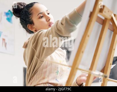 Laisser libre cours à la créativité. Photo en bas angle d'une jeune femme attrayante peint sur une toile dans son studio. Banque D'Images