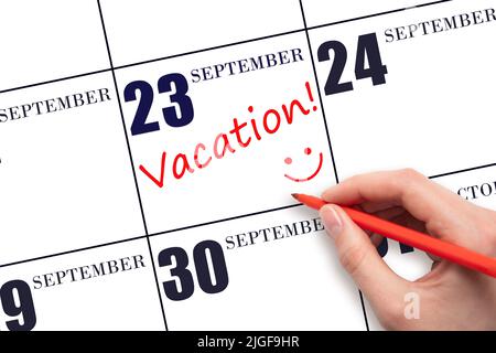 23rd jour de septembre. Une main écrivant un TEXTE DE VACANCES et dessinant un visage souriant sur une date de calendrier 23 septembre . Concept de planification des vacances. Automne m Banque D'Images