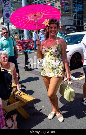 Poole, Dorset, Royaume-Uni, 10 juillet 2022. Poole Goes Vintage costume rétro, musique et festival de danse sur Poole Quay sous un soleil brûlant. Une femme avec un parapluie rose est habillée de la partie pour l'événement. Paul Biggins/Alamy Live News Banque D'Images