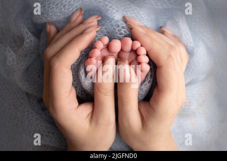 Les paumes du père, la mère tient le pied du nouveau-né. Pieds de bébé sur les paumes des parents. Banque D'Images