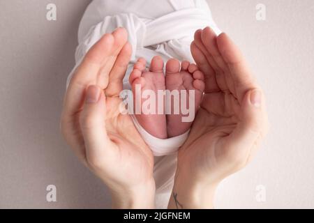 Les paumes du père, la mère tient le pied du nouveau-né. Pieds de bébé sur les paumes des parents. Banque D'Images