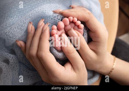 Les paumes du père, la mère tient le pied du nouveau-né. Pieds de bébé sur les paumes des parents. Banque D'Images