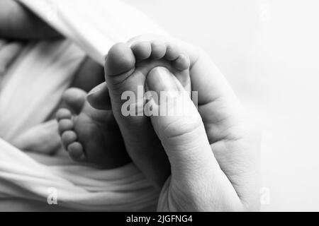 Les paumes du père, la mère tient le pied du nouveau-né. Pieds de bébé sur les paumes des parents. Banque D'Images