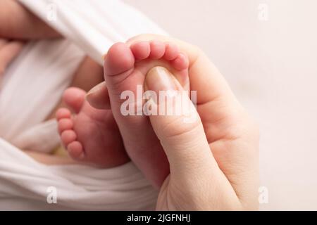 Les paumes du père, la mère tient le pied du nouveau-né. Pieds de bébé sur les paumes des parents. Banque D'Images