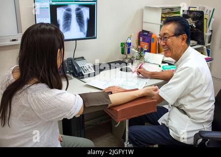 Médecin prend la pression artérielle des patients à la clinique médicale, Ota, Tokyo, Japon Banque D'Images