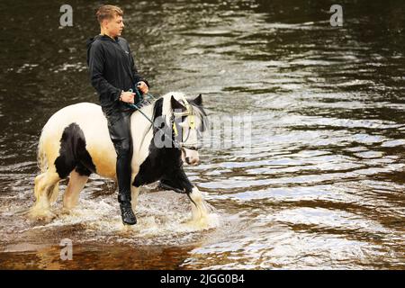 Un adolescent à cheval dans la rivière Eden, Appleby Horse Fair, Appleby dans Westmorland, Cumbria Banque D'Images