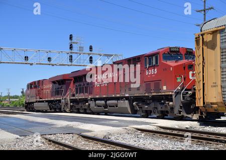 Franklin Park, Illinois, États-Unis. Les locomotives du chemin de fer canadien Pacifique dirigent un train de marchandises par un passage à niveau et sous un pont de signalisation. Banque D'Images