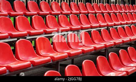 Rangées de sièges de stade extérieurs rouges vides en perspective, arrière-plan sportif Banque D'Images