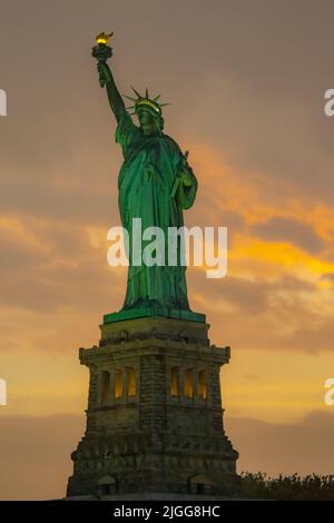 Vue rapprochée de la Statue de la liberté sur un coucher de soleil nuageux Banque D'Images