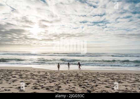 Trois enfants jouant à la plage au Portugal par une journée nuageux et lumineuse Banque D'Images