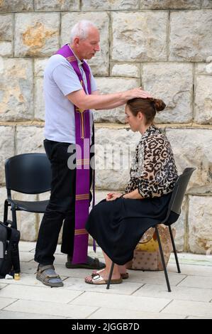Un prêtre qui pond les mains et bénit une femme en conclusion d'une confession pendant Mladifest 2021, le festival de la jeunesse à Medjugorje. Banque D'Images
