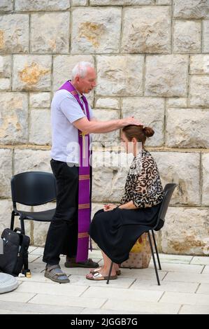 Un prêtre qui pond les mains et bénit une femme en conclusion d'une confession pendant Mladifest 2021, le festival de la jeunesse à Medjugorje. Banque D'Images