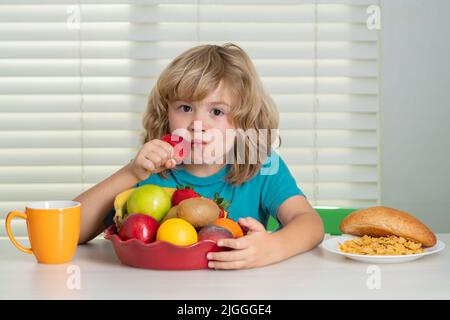 L'enfant mange des fraises, des fruits biologiques. Enfant préadolescent garçon de 7, 8, 9 ans manger des légumes sains. Petit déjeuner avec lait, fruits et légumes Banque D'Images