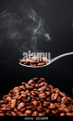 Une cuillère à café suffit. Photo de grains de café sur fond gris. Banque D'Images