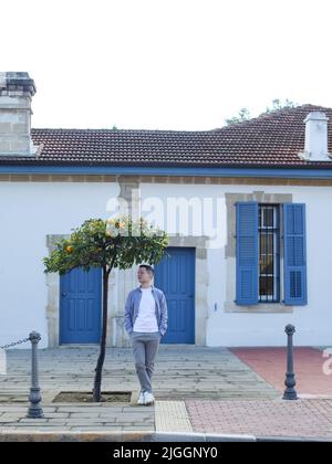 L'homme se trouve près d'un beau bâtiment avec des portes et des fenêtres bleues à Chypre Banque D'Images