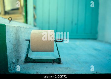 Un rouleau de papier toilette simple pli le moins cher sur un support de papier toilette dans une toilette extérieure rurale Banque D'Images