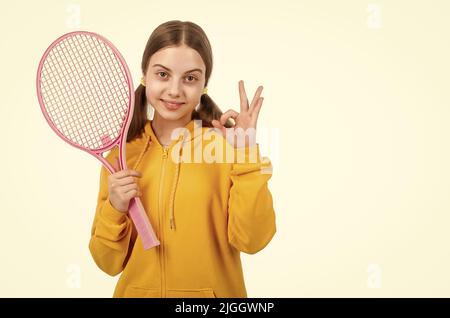 fille gaie enfant tenir le tennis ou le badminton raquette et montrer le geste ok, enfance saine. Banque D'Images