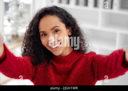 Selfie de Noël rapide. Une jeune femme prend un selfie tout en célébrant Noël à la maison. Banque D'Images