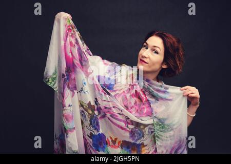 Une femme heureuse dans une robe asiatique sur un fond noir de studio. Femme souriante sur fond sombre Banque D'Images