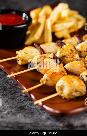 Brochettes de poulet. Morceaux de filet de poulet tendre, grillé avec des rondelles d'oignon doux, et garni de frites et de sauce tomate tendre (non épicée). Banque D'Images