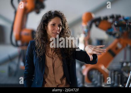 Une femme ingénieur en automatisation s'est occupée de programmer un bras robotique en usine. Banque D'Images