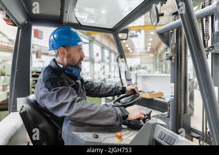 Happy mature homme chariot élévateur chariot élévateur conducteur levage palette dans l'entrepôt de stockage . Banque D'Images