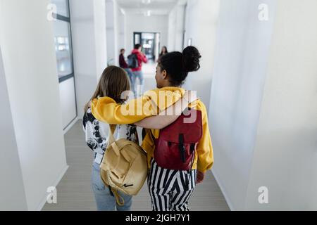 Vue arrière des jeunes élèves du secondaire qui marchent dans le couloir à l'école, concept de retour à l'école. Banque D'Images