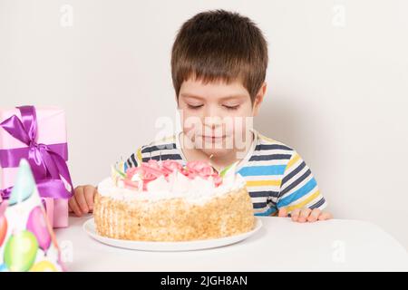 Le garçon d'anniversaire souffle les bougies sur le gâteau d'anniversaire Banque D'Images