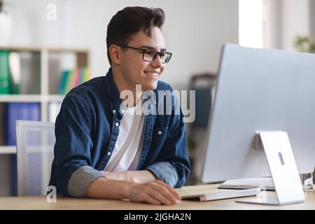 Portrait d'un homme d'affaires millénaire souriant travaillant sur l'ordinateur au bureau Banque D'Images