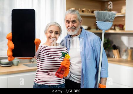 Application Service de nettoyage Couple senior montrant un téléphone intelligent vierge dans la cuisine Banque D'Images