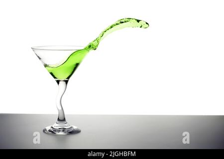 cocktail vert éclaboussant d'un verre de martini Banque D'Images