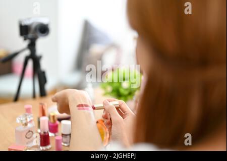 Gros plan, belle blogueuse de beauté millénaire influenceur faisant une vidéo sur les cosmétiques, testant le rouge à lèvres sur sa main. Banque D'Images