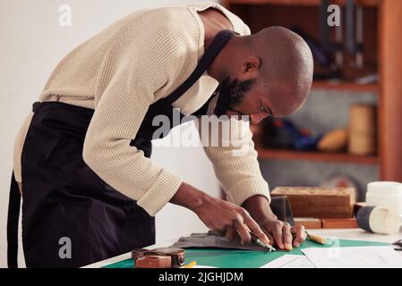 Concentré sur l'artisanat. Un beau jeune homme designer travaillant avec le cuir dans son studio de design. Banque D'Images