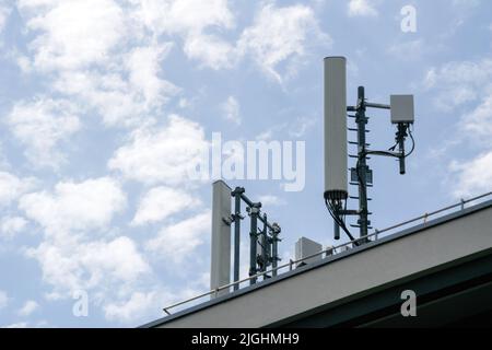 Antenne multiple sur le toit d'une maison avec nuages épars en arrière-plan 5G 4G LTE Banque D'Images