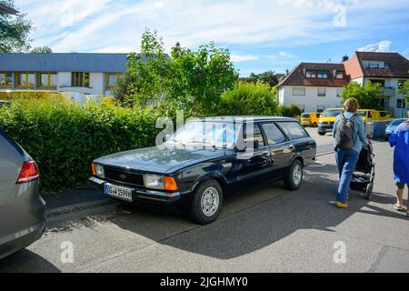 Oberkirch, Allemagne - 27 mai 2022: Les femmes allemandes marchant près de la voiture de voiture Ford vintage garée dans le centre-ville près du bureau de poste DHL Banque D'Images