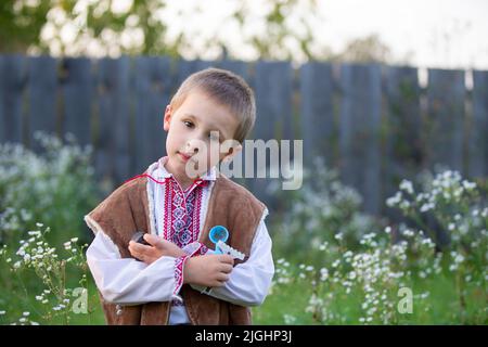 Petit garçon slave biélorusse ou ukrainien dans des vêtements nationaux sur un fond rustique. Banque D'Images