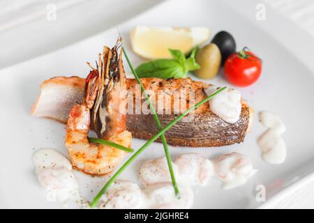 Saumon grillé, crevettes à la sauce sur une assiette blanche Banque D'Images