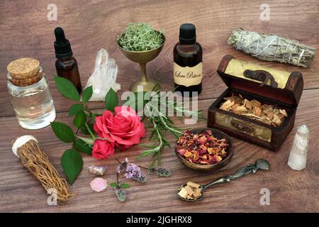 La potion d'amour et les ingrédients aphrodisiaques pour le charme magique avec des herbes, la fleur de rose, le bâton de taches, l'huile et les cristaux de quartz. Banque D'Images