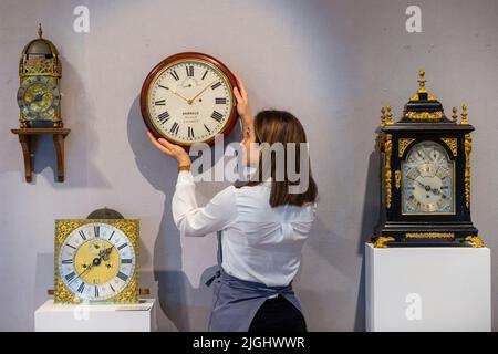 Londres, Royaume-Uni. 11 juillet 2022. Un technicien présente « une montre murale en acajou inhabituelle avec échappement de détente et régulation de cadran avant » (est. £2 000 - £3 000) à un aperçu de la vente des belles horloges de Bonhams à leur galerie New Bond Street. Les lots seront mis aux enchères le 14 juillet. Credit: Stephen Chung / Alamy Live News Banque D'Images