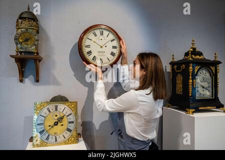 Londres, Royaume-Uni. 11 juillet 2022. Un technicien présente « une montre murale en acajou inhabituelle avec échappement de détente et régulation de cadran avant » (est. £2 000 - £3 000) à un aperçu de la vente des belles horloges de Bonhams à leur galerie New Bond Street. Les lots seront mis aux enchères le 14 juillet. Credit: Stephen Chung / Alamy Live News Banque D'Images