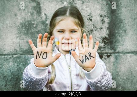 Belle et effrayé inscription d'enfant PAS DE GUERRE sur ses mains. L'invasion de l'Ukraine par la Russie, les enfants contre la guerre Banque D'Images