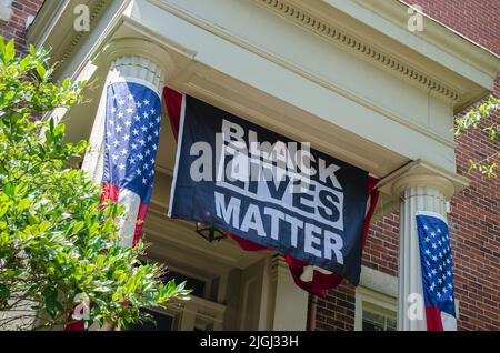 Une photo sous angle d'une bannière Black Lives Matter sur un bâtiment avec des drapeaux américains Banque D'Images