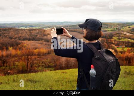 Le modèle féminin d'âge moyen fait la photo des montagnes sur le smartphone Banque D'Images