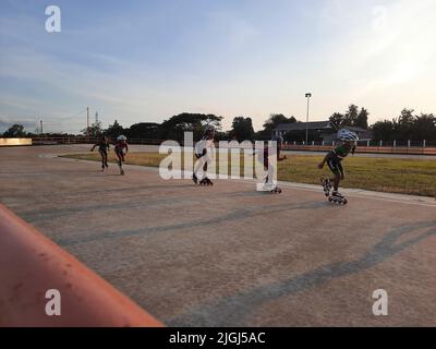 Jeune patineur mixte en ligne tout en s'entraîner sur une piste en plein air au stadion Pacar à Bantul, Yogyakarta, Indonésie. Banque D'Images