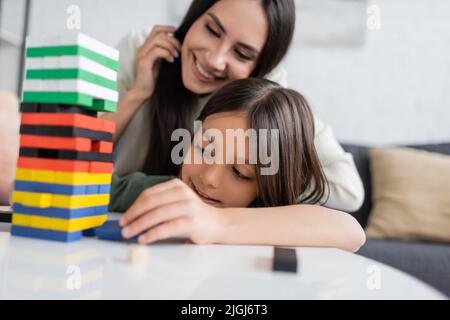 bonne baby-sitter jouer à un jeu de tour en bois avec une fille heureuse dans le salon Banque D'Images